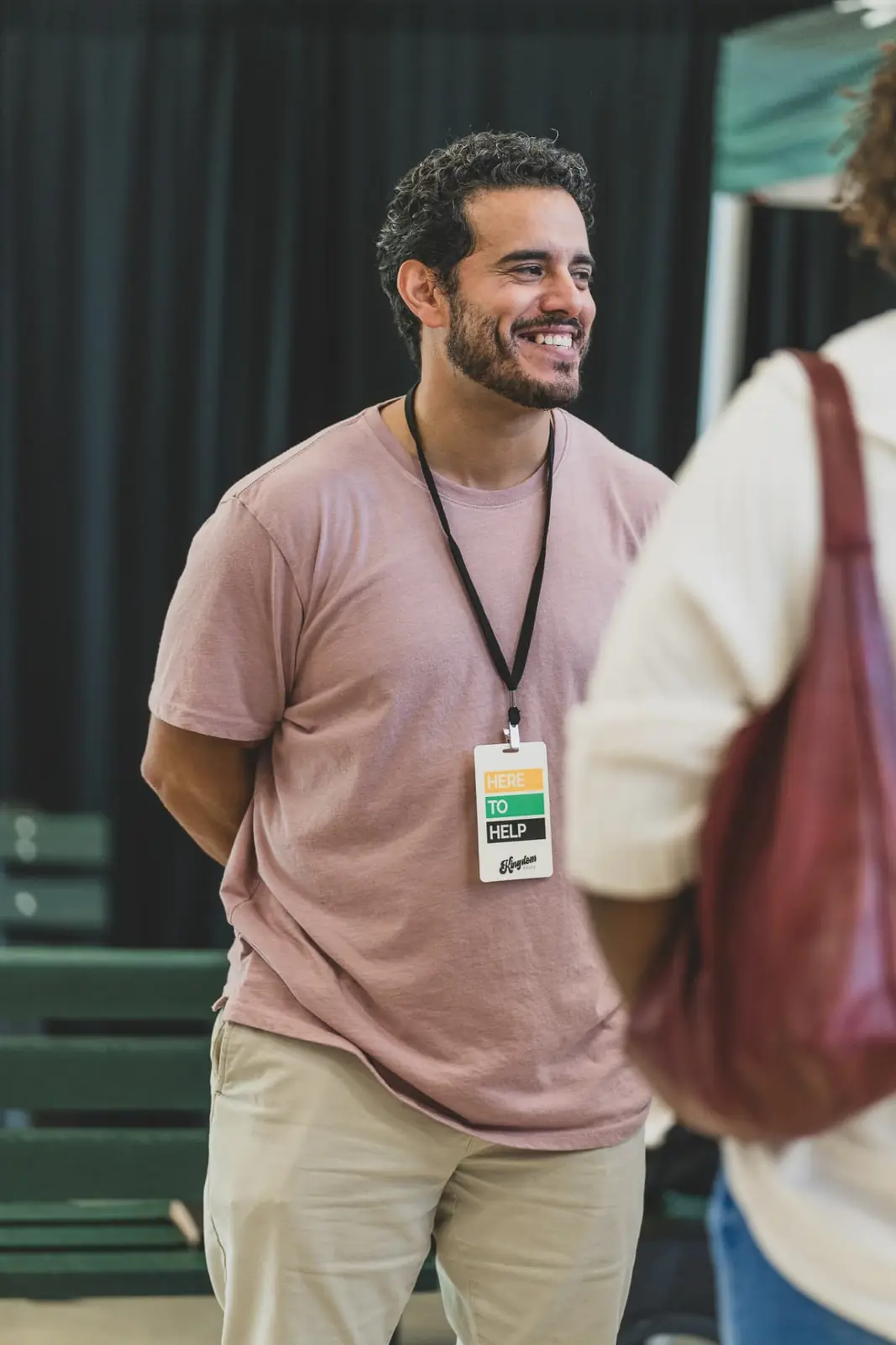 A Kingdom House volunteer wearing a Here to Help badge greeting a guest