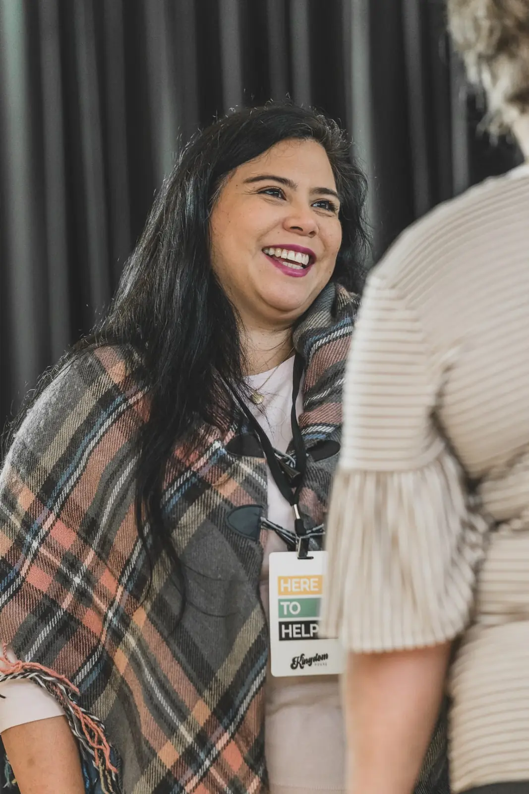A Kingdom House volunteer wearing a Here To Help badge welcoming a guest