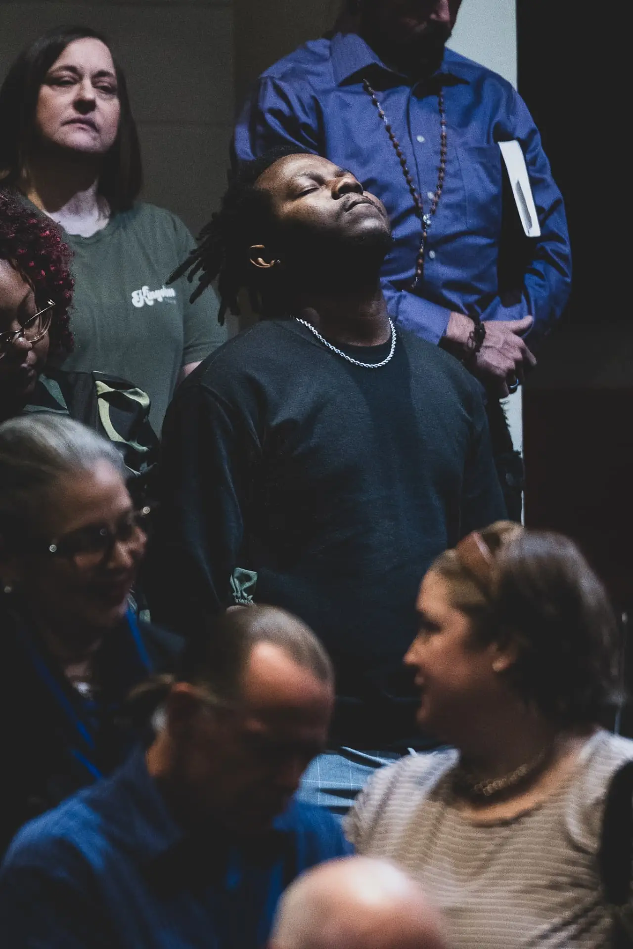 A man surrounded by his church family, eyes closed in worship