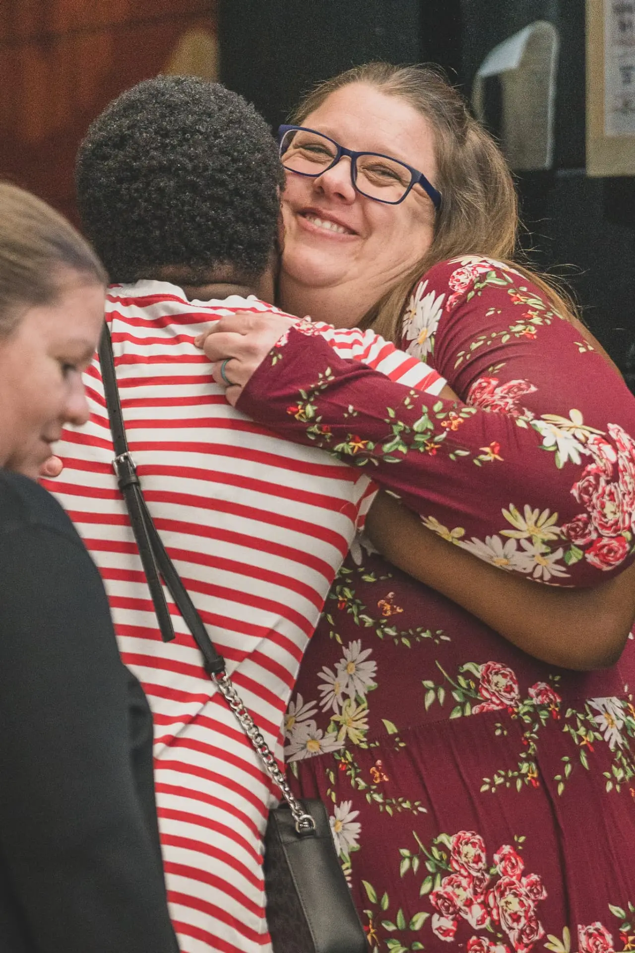 Two women from different backgrounds sharing a warm hug